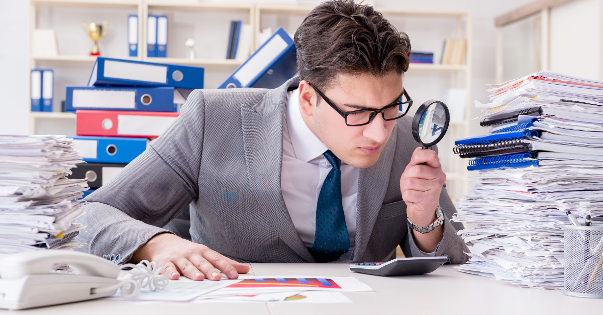 An auditor looking closely over documents.