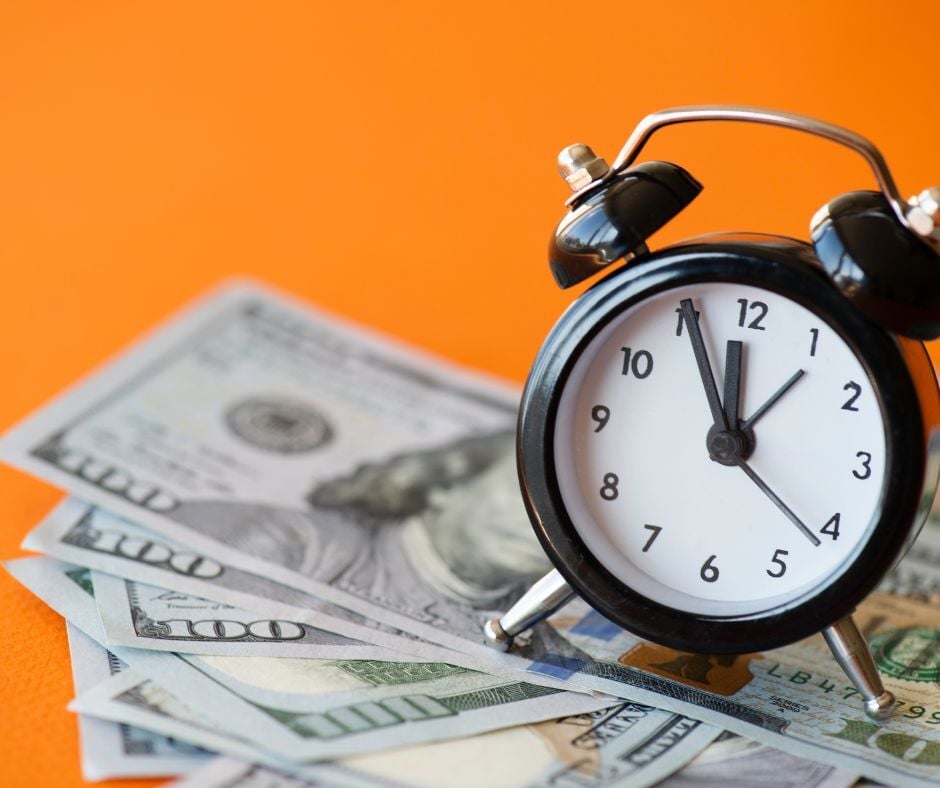 A clock sitting on top of money.