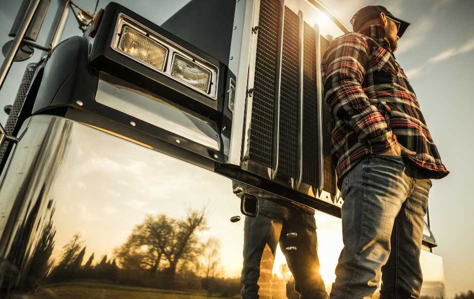 A truck driver standing in front of his rig.